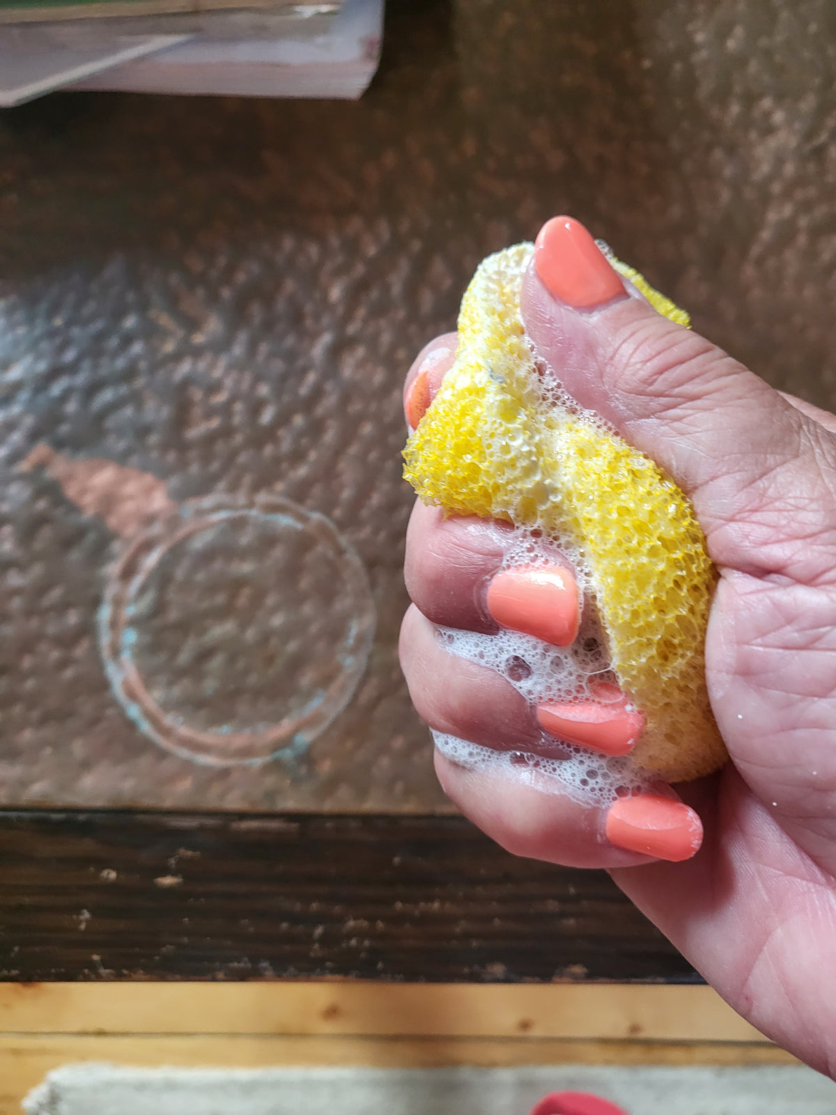 Squeezing sponge with cleanser on it.