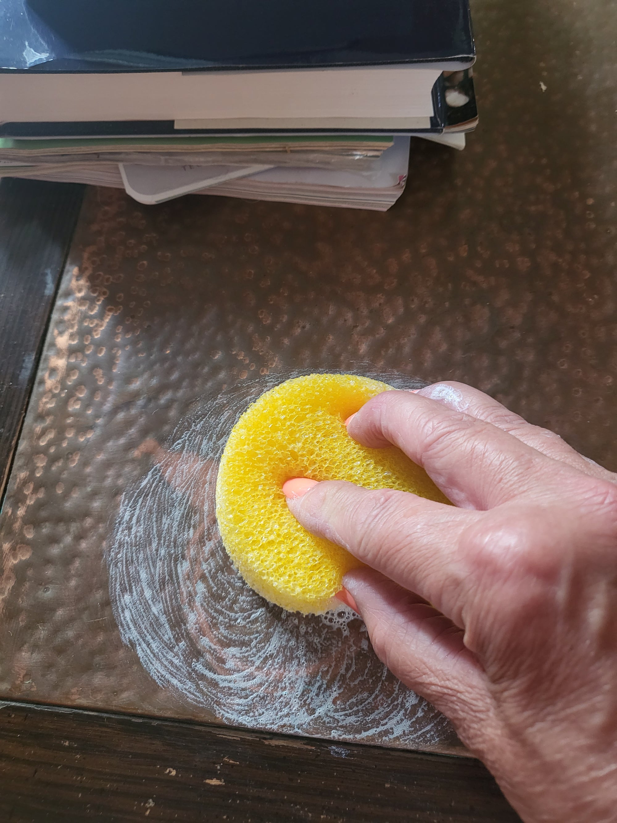 Wiping the cleanser on to a copper table surface.
